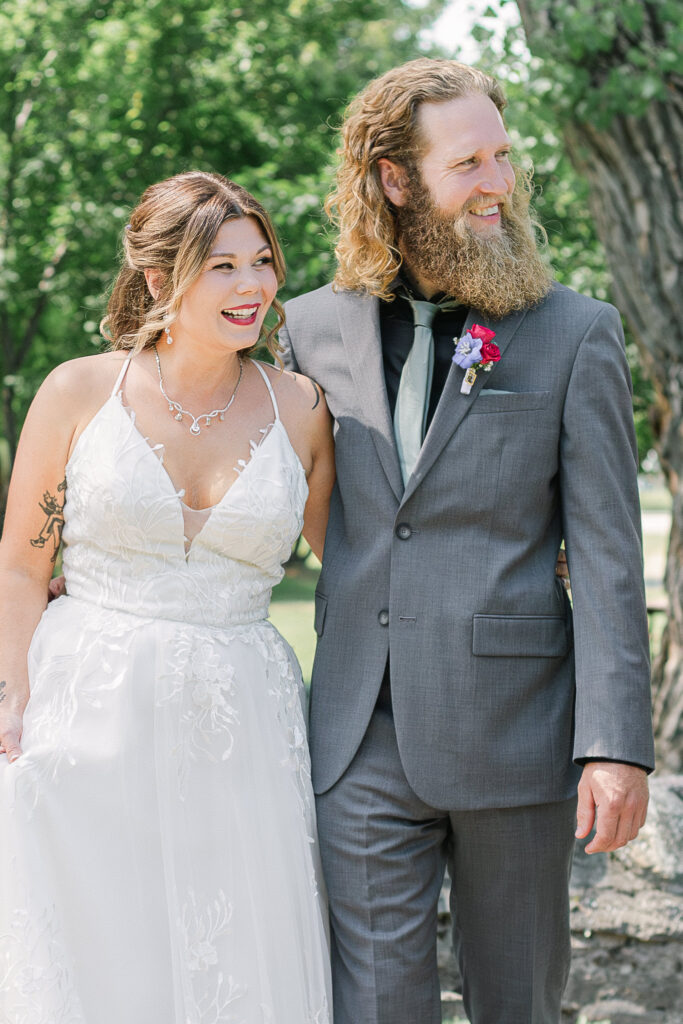 Bride and groom walking together and smiling at Bella’s Castle in Morden Manitoba during wedding day with soft natural light